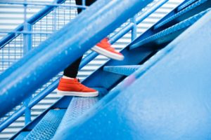 red shoed feet walking up blue metal staircase