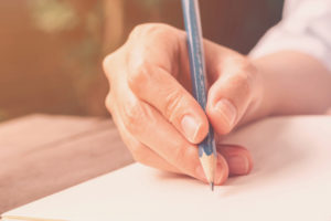 close up hand woman writing notebook in coffee shop