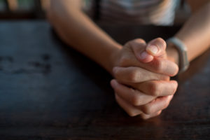 close up of hands folded praying