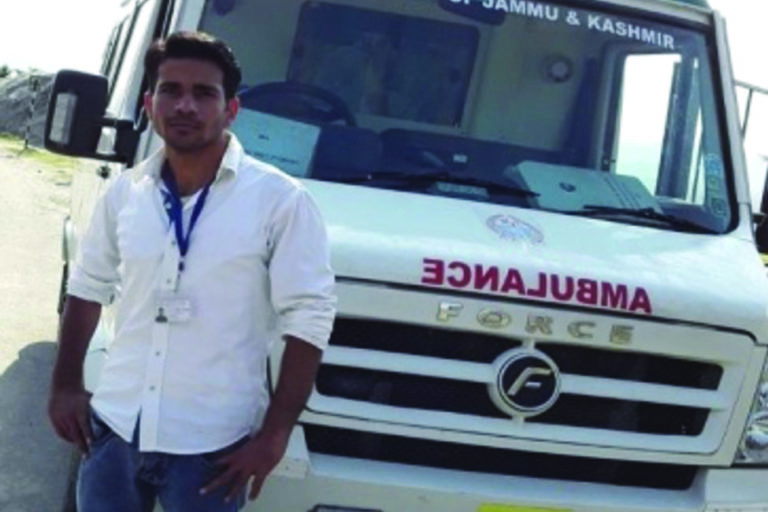 Young indian man posing in front of ambulance